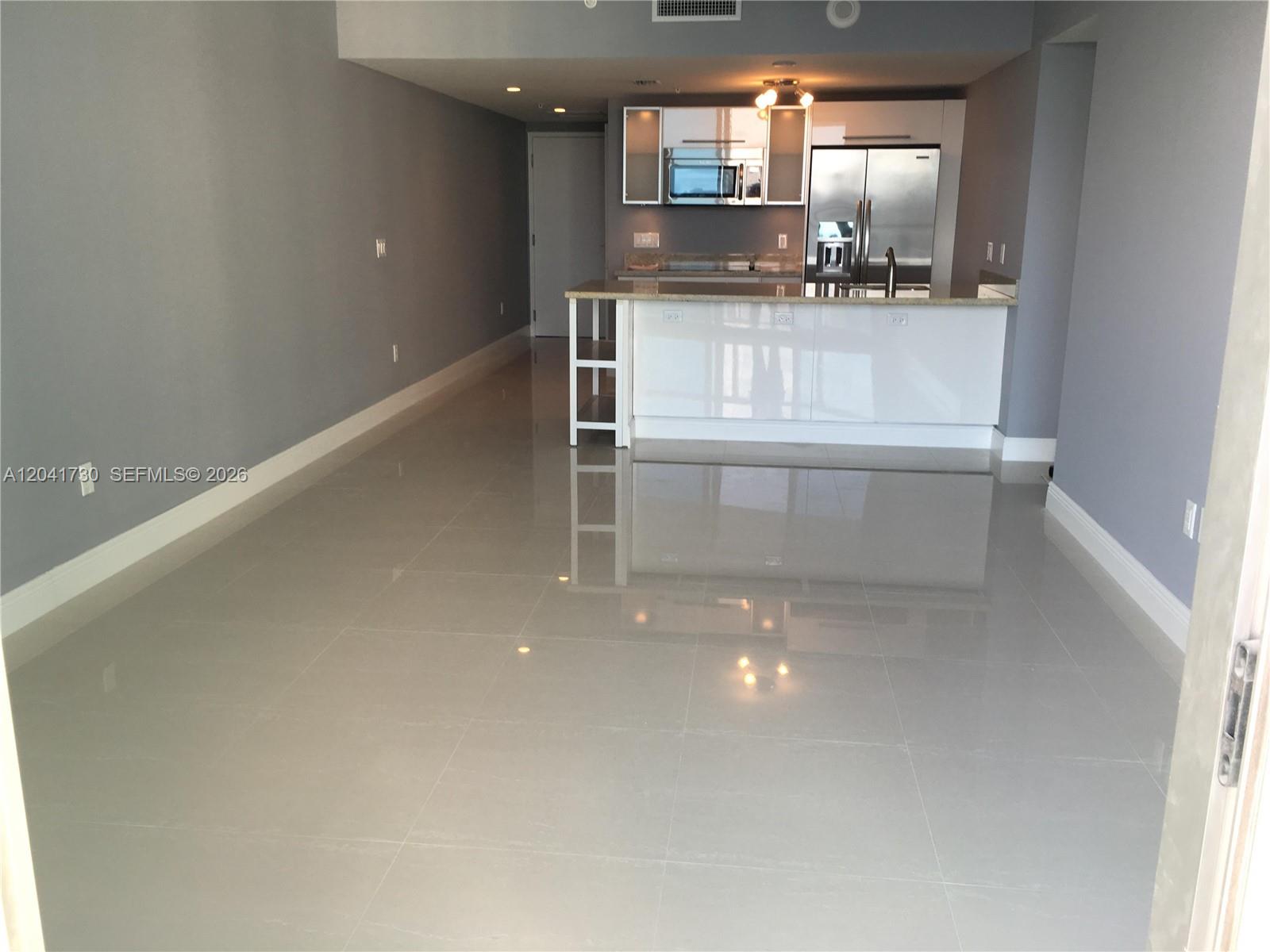 An open-concept kitchen features white cabinetry, stainless steel appliances, and glossy tile flooring — 185 SW 7th St # 2104, Miami FL 33130, MIAMI, FL