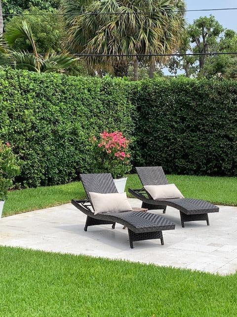 Two dark wicker lounge chairs with beige pillows sit on a stone patio outdoors — 839 Upland Road, West Palm Beach FL 33401, WEST PALM BEACH, FL