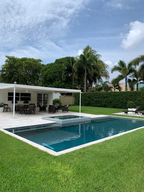A swimming pool with an attached spa sits in a backyard next to a patio — 839 Upland Road, West Palm Beach FL 33401, WEST PALM BEACH, FL