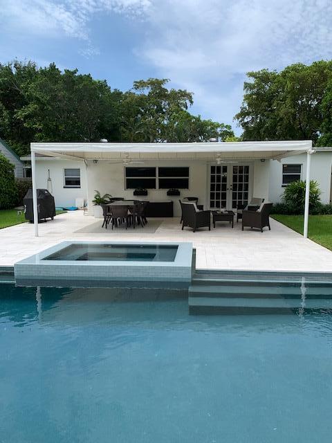 A backyard features a swimming pool with a spa, a covered patio, and outdoor furniture — 839 Upland Road, West Palm Beach FL 33401, WEST PALM BEACH, FL