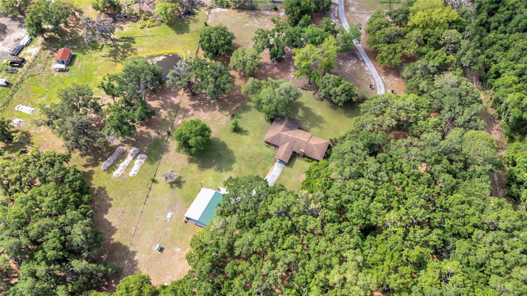 An aerial view shows a house, a detached garage, and a pond on a wooded lot — 1520 LEGACY WOODS COURT, GROVELAND, FL