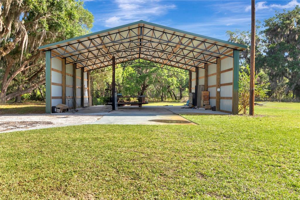 An open-sided metal carport with a concrete slab floor stands in a grassy yard — 1520 LEGACY WOODS COURT, GROVELAND, FL