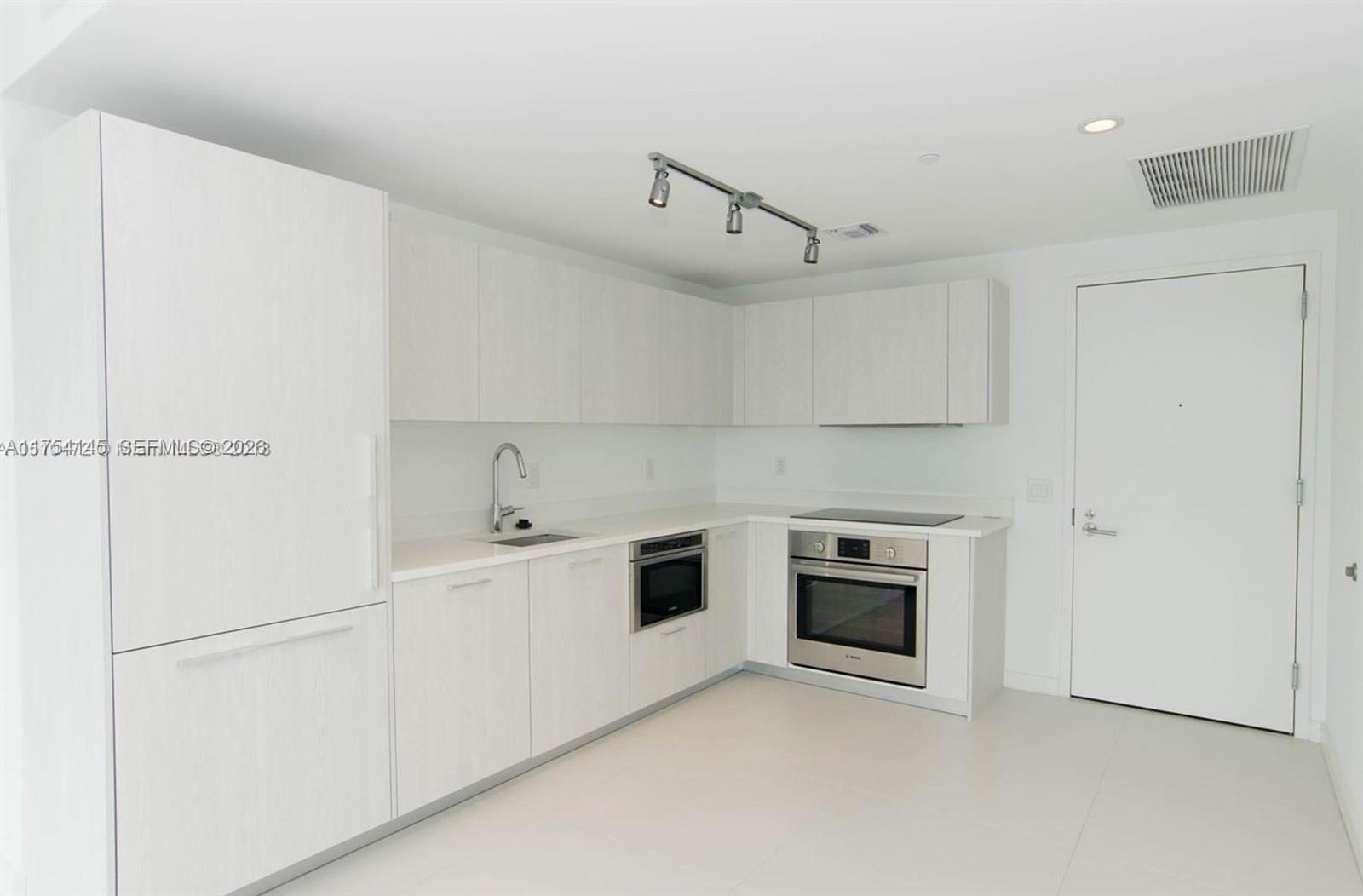 A modern kitchen features white cabinetry, stainless steel appliances, and light-colored tile flooring — 501 NE 31st St # 2009, Miami FL 33137, MIAMI, FL