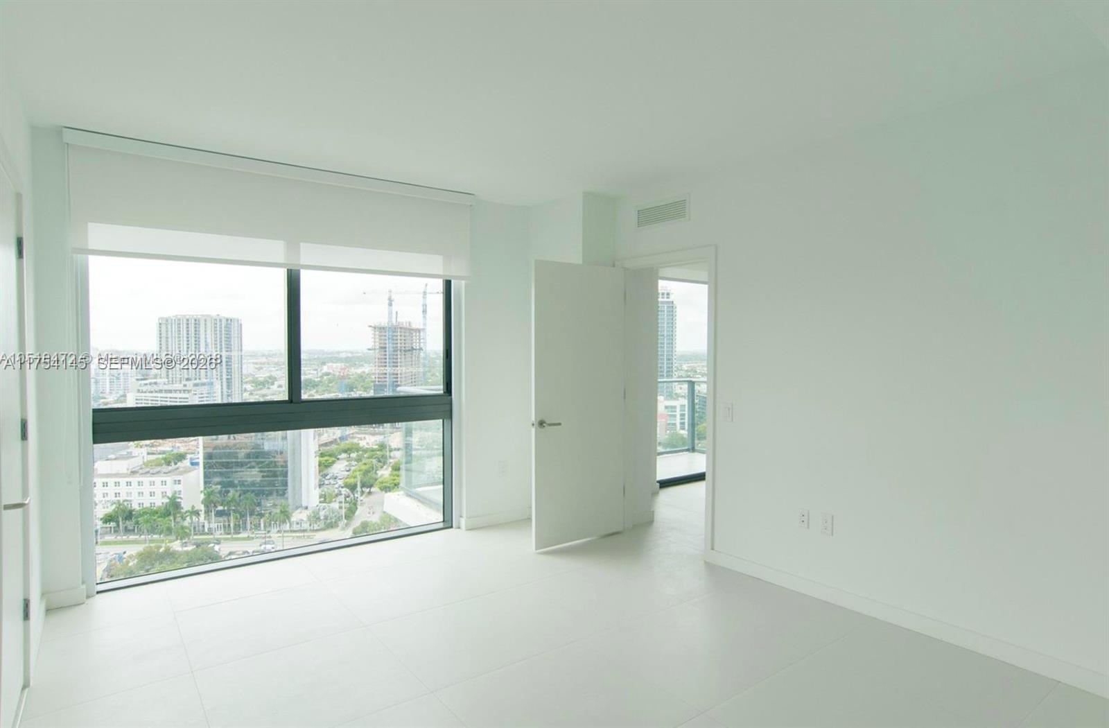 A bright, minimalist room features white tile floors, floor-to-ceiling windows, and an open doorway — 501 NE 31st St # 2009, Miami FL 33137, MIAMI, FL