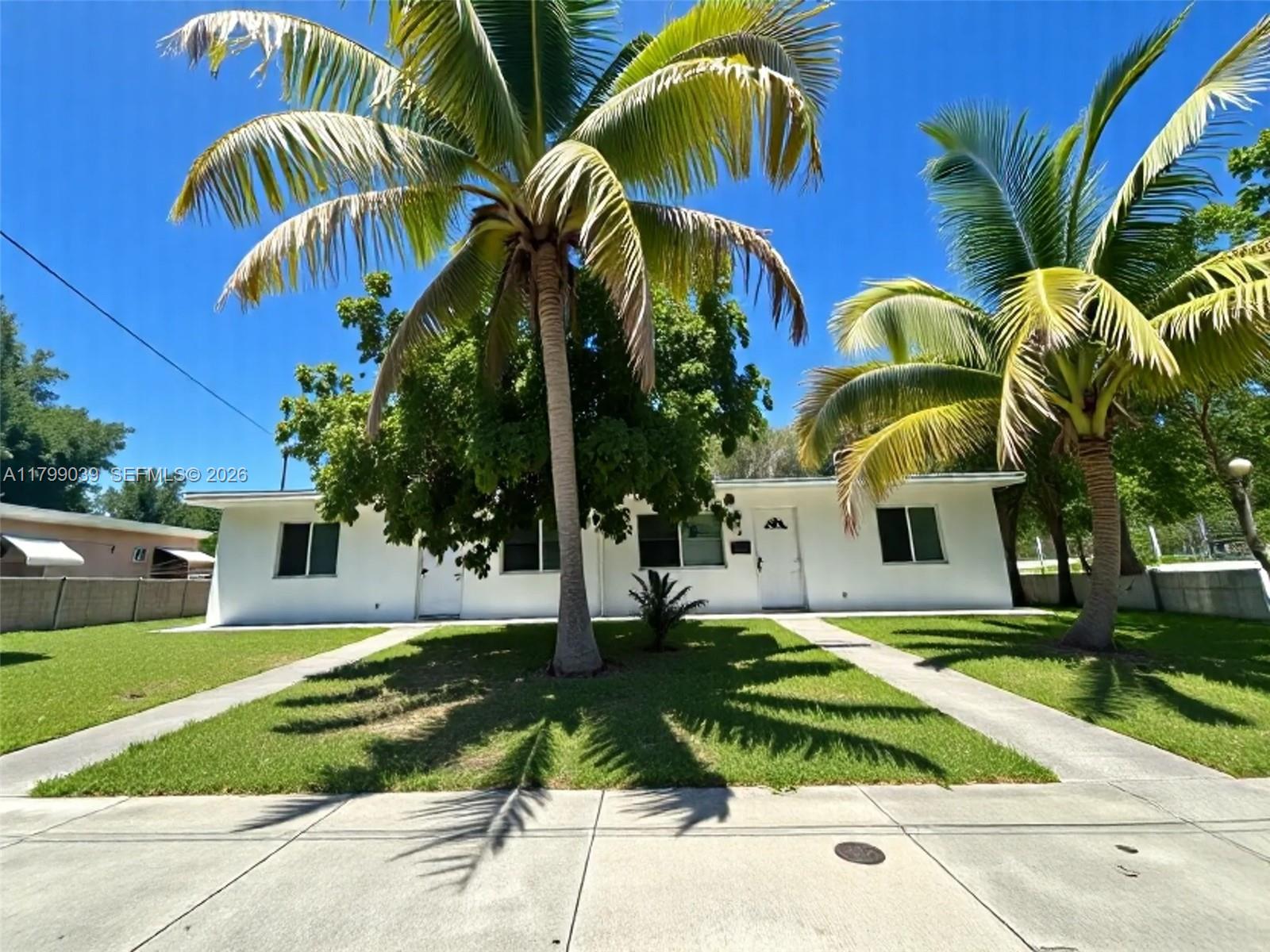 A white single-story house features two front doors, palm trees, and a grassy front yard — 16204 NE 18th Ct, North Miami Beach FL 33162, NORTH MIAMI BEACH, FL