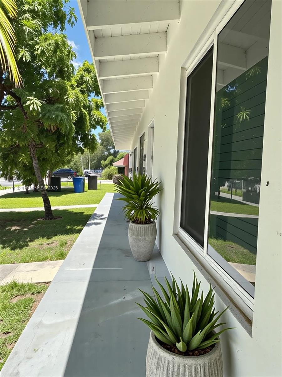 A concrete walkway runs along the side of a white building with potted plants — 16204 NE 18th Ct, North Miami Beach FL 33162, NORTH MIAMI BEACH, FL