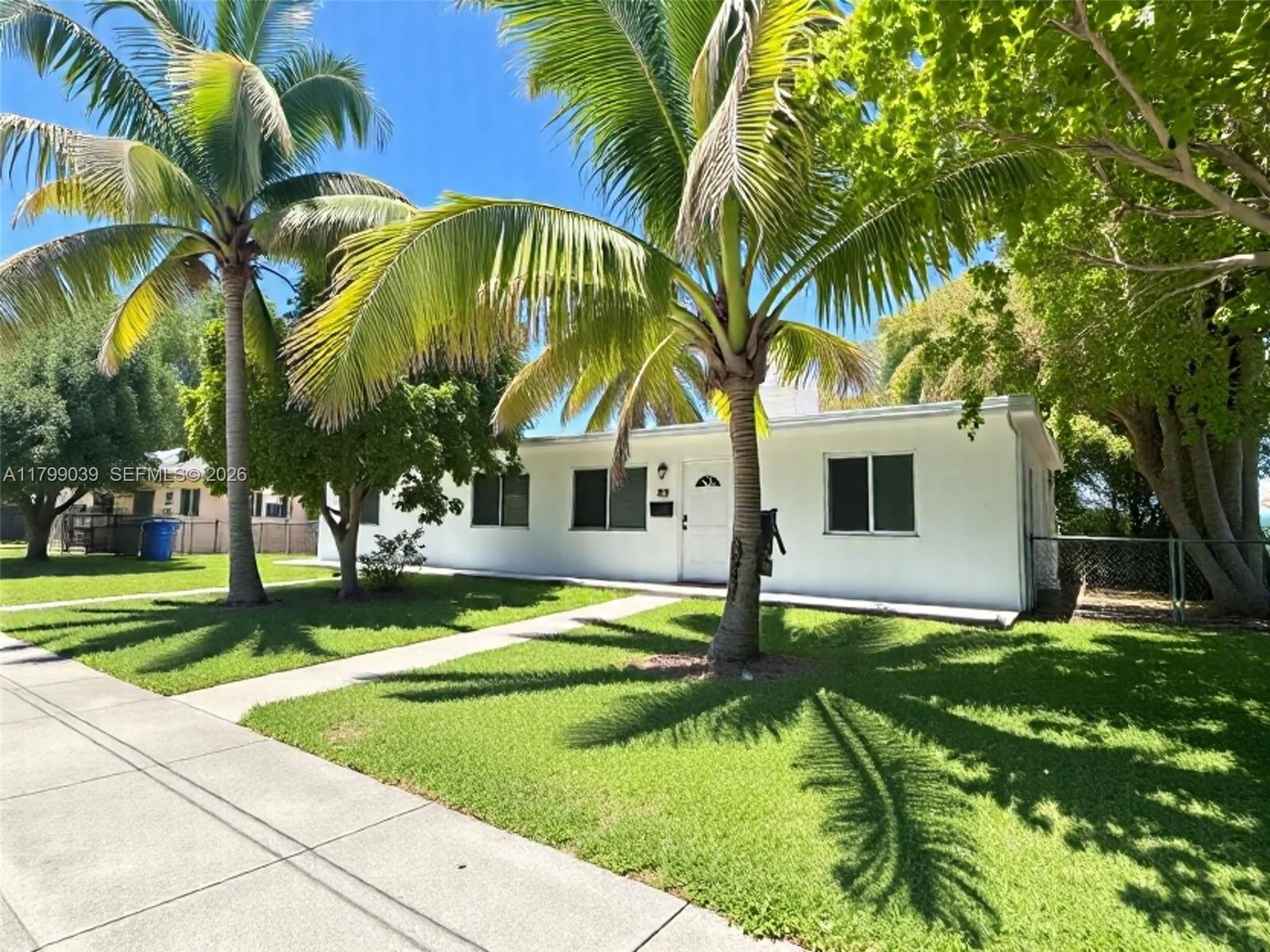 A white, single-story house features a front lawn with palm trees and a walkway — 16204 NE 18th Ct, North Miami Beach FL 33162, NORTH MIAMI BEACH, FL