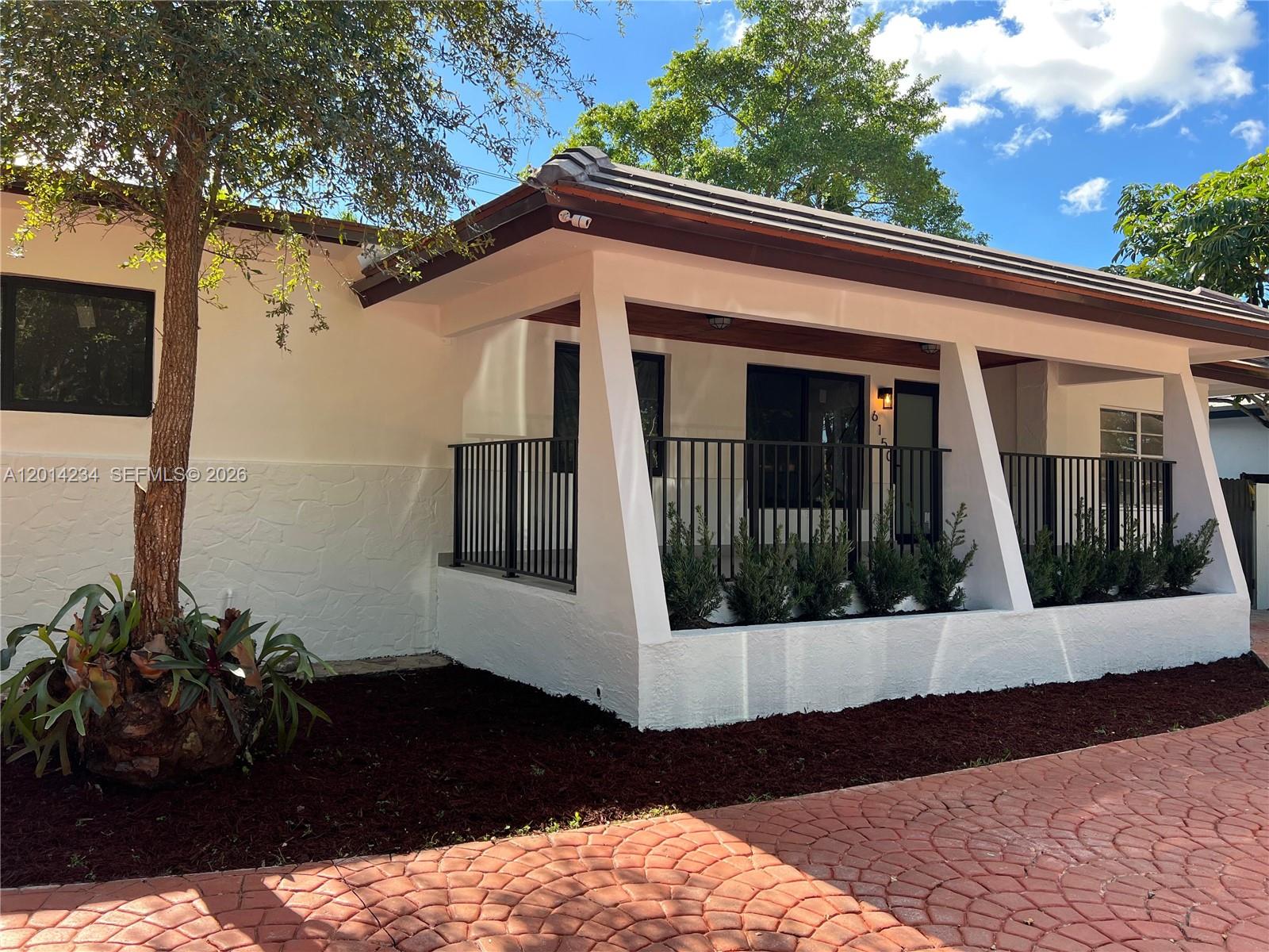A white house exterior features a covered porch with black railings and angled support columns — 6150 SW 16th St, West Miami FL 33155, WEST MIAMI, FL