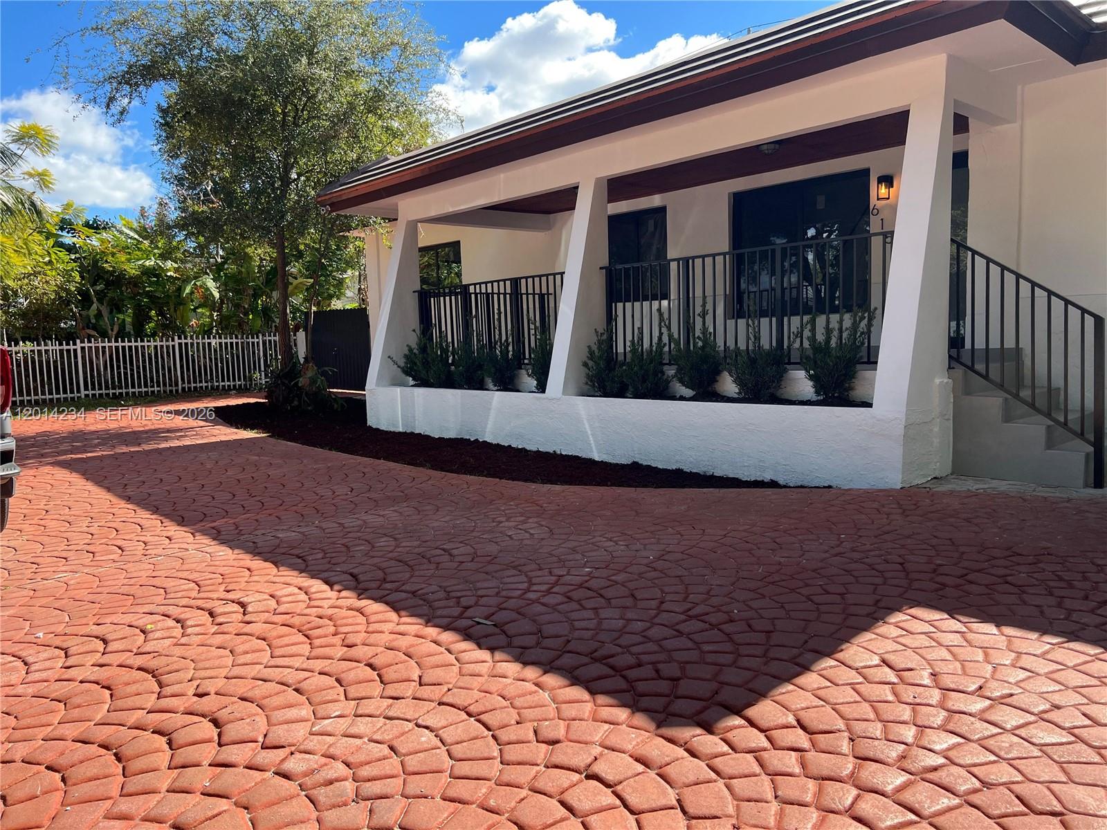 A white house with a red patterned driveway and a covered porch with black railings — 6150 SW 16th St, West Miami FL 33155, WEST MIAMI, FL