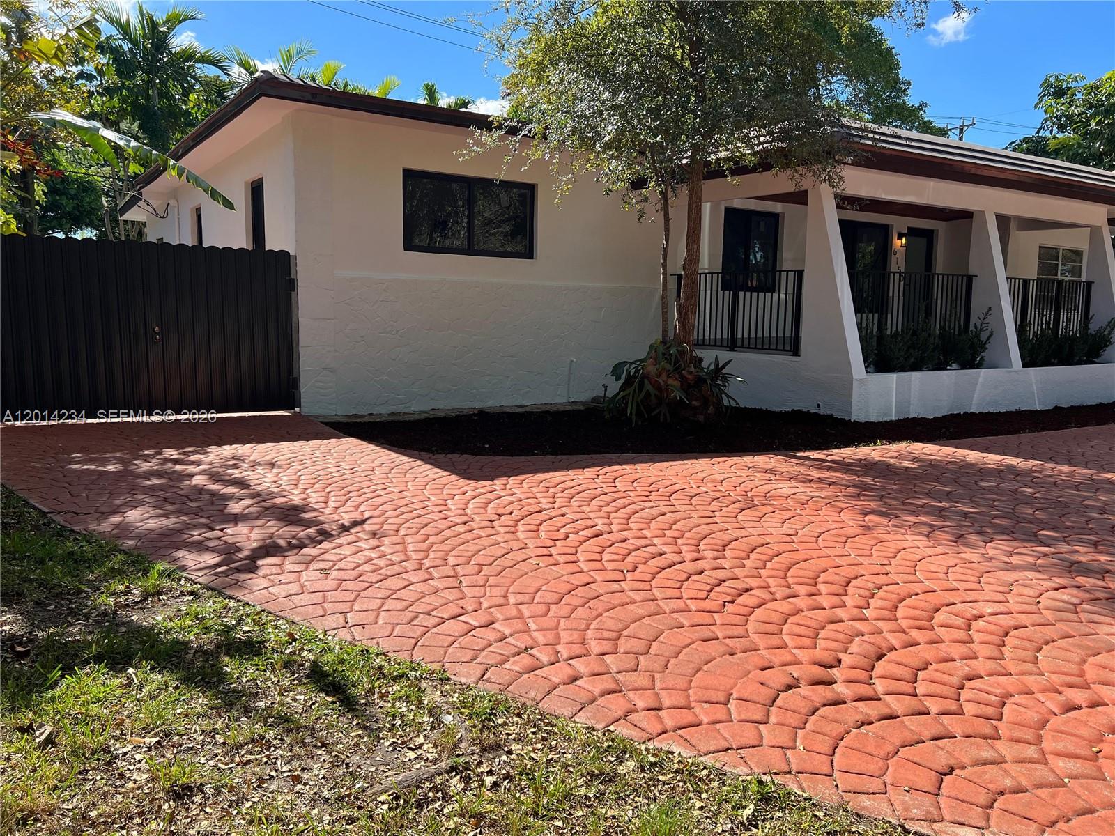 A white house with a red patterned driveway and a black fence under a tree — 6150 SW 16th St, West Miami FL 33155, WEST MIAMI, FL