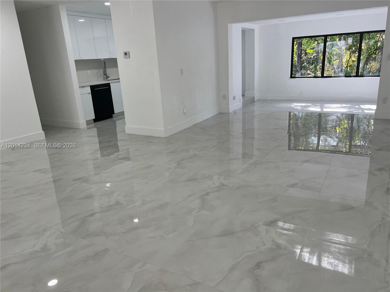 A bright, open-concept living area features polished marble-look tile flooring and a modern white kitchen — 6150 SW 16th St, West Miami FL 33155, WEST MIAMI, FL