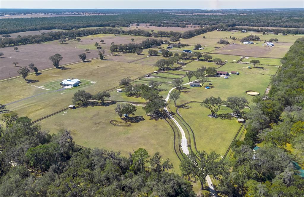 An aerial view shows a large rural property with fenced pastures, scattered trees, and buildings — 4700 NW 157TH COURT, MORRISTON, FL