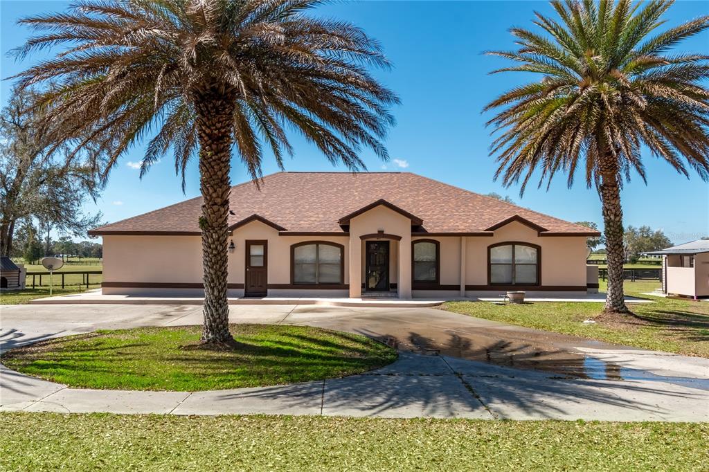 A single-story house with a tan exterior, brown trim, and two large palm trees — 4700 NW 157TH COURT, MORRISTON, FL