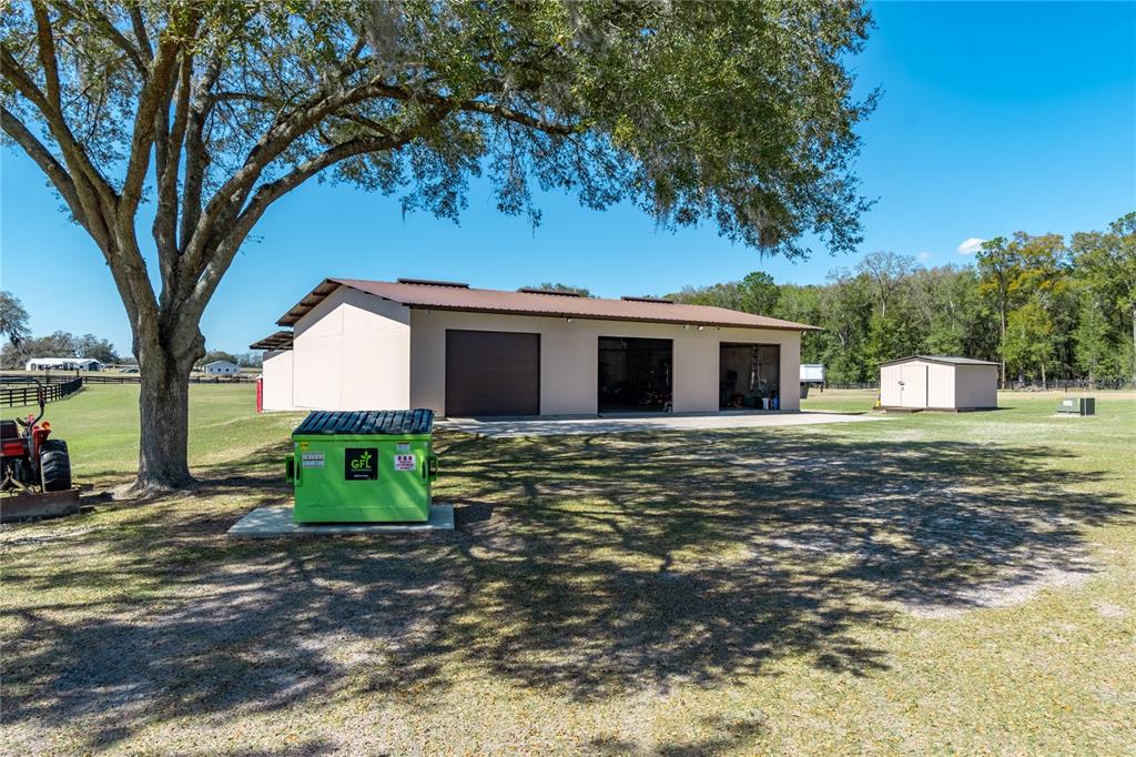 A large metal workshop building stands on a grassy lot with a green dumpster nearby — 4700 NW 157TH COURT, MORRISTON, FL