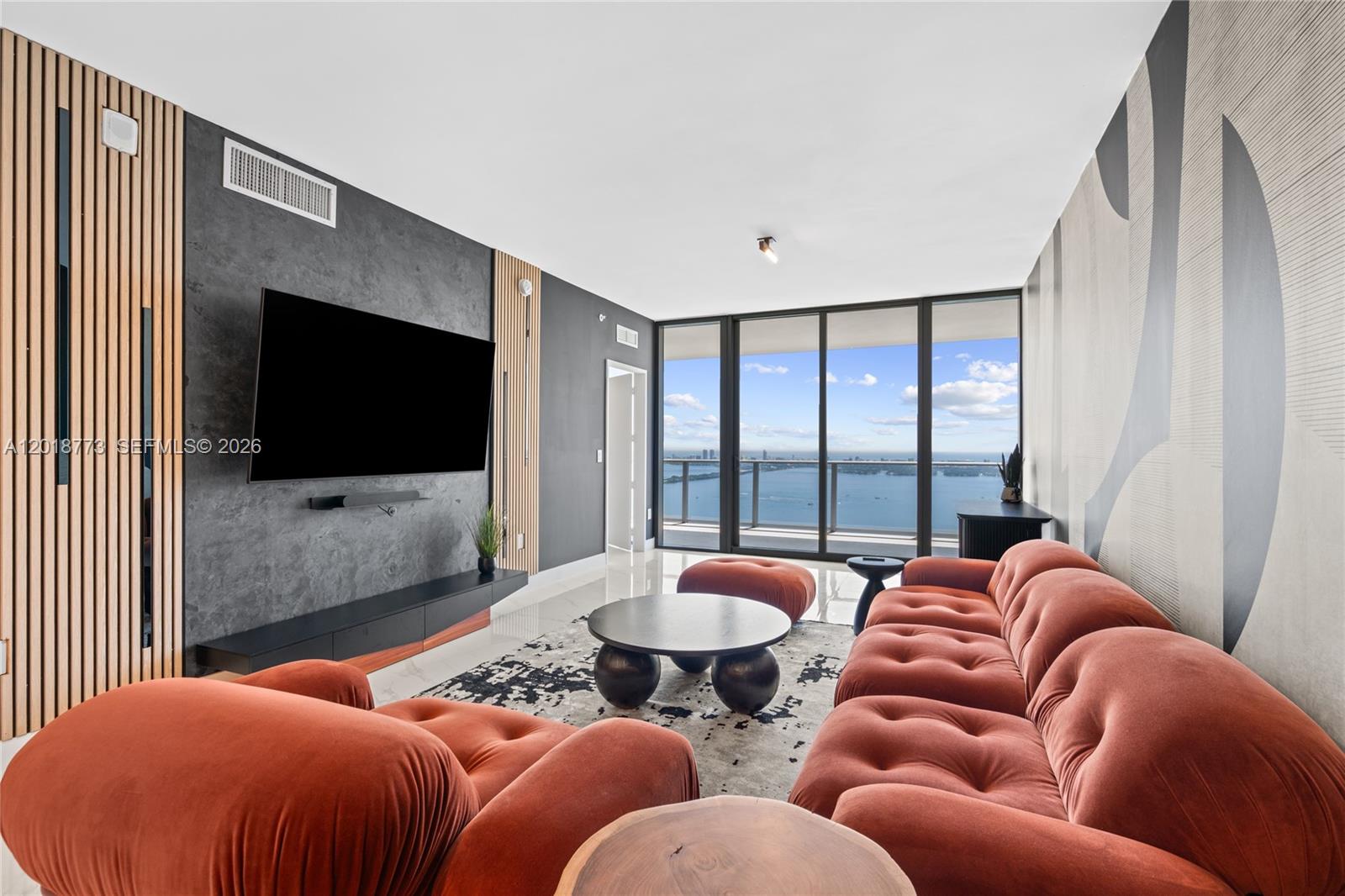 A modern living room features a rust-colored tufted sofa, a dark accent wall, and floor-to-ceiling windows — 700 NE 24th St # 5206, Miami FL 33137, MIAMI, FL