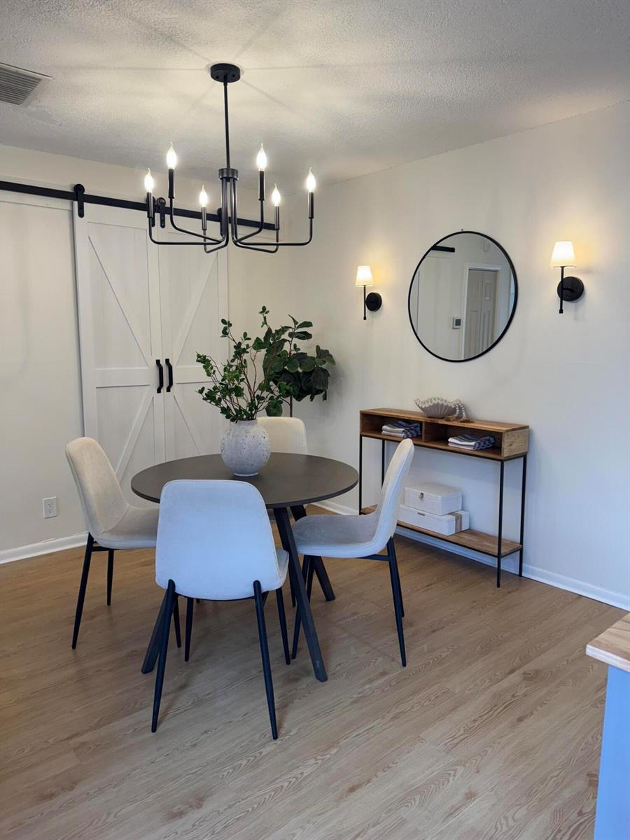 A dining room features a round table, four chairs, a console table, and a chandelier — 6372 Seven Springs Boulevard # A, FL 33463, FL