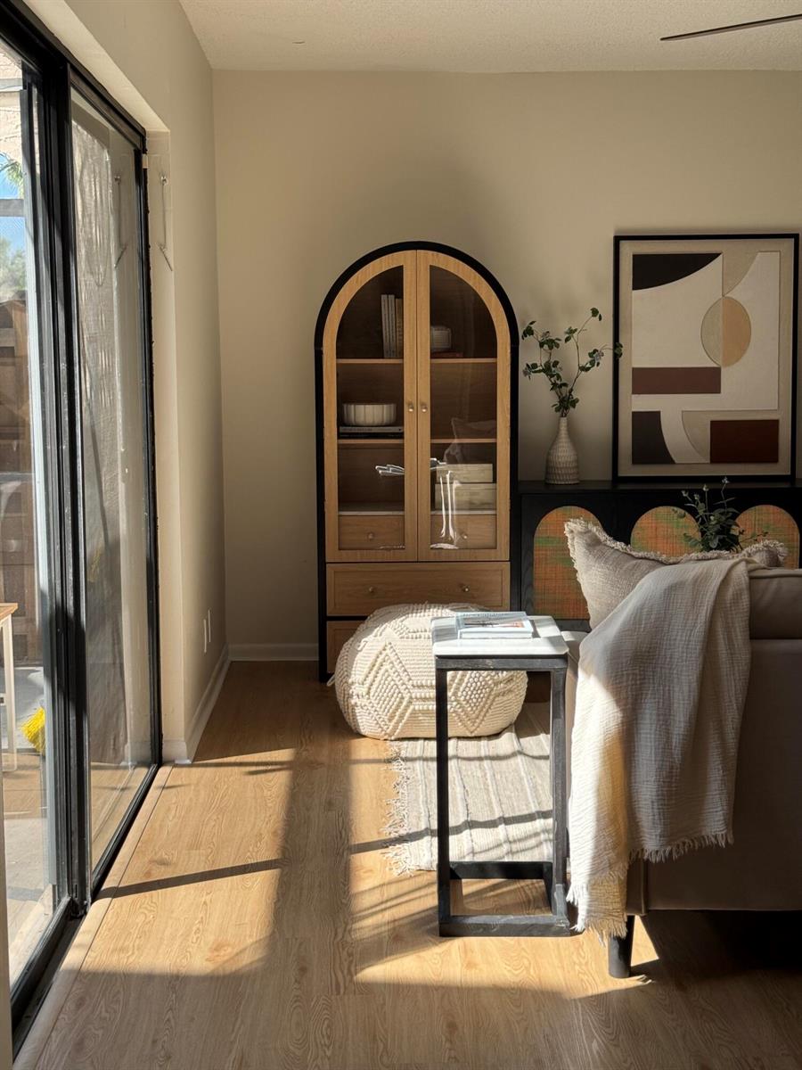 A living room features a wooden arched cabinet, a side table, and a textured pouf — 6372 Seven Springs Boulevard # A, FL 33463, FL