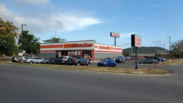 An exterior view of an AutoZone store with a parking lot and surrounding landscape — PR 584 PR-584 INT. PR-149, JUANA DIAZ, PR