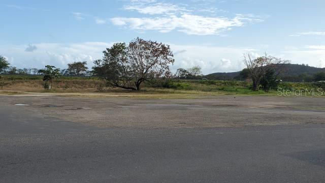An expansive, paved lot sits in front of a grassy field with scattered trees — PR 584 PR-584 INT. PR-149, JUANA DIAZ, PR