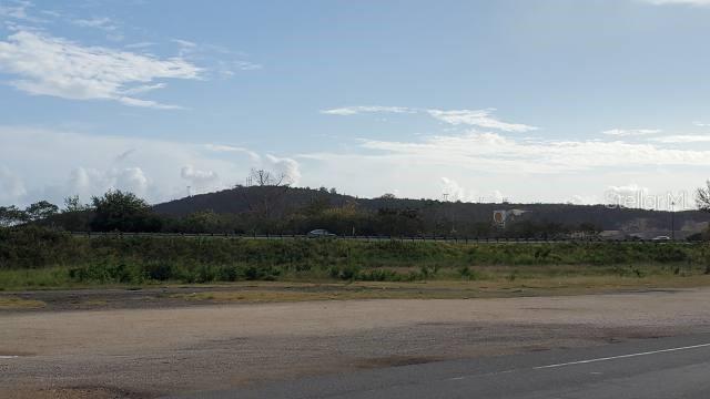 A view of a grassy field with a road and a distant hill under clouds — PR 584 PR-584 INT. PR-149, JUANA DIAZ, PR