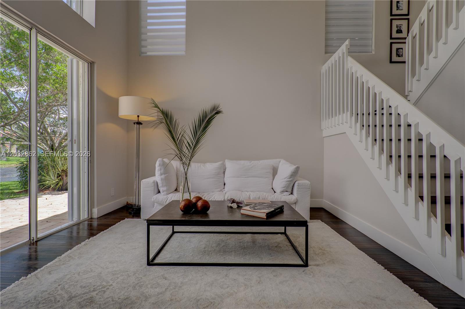 A living room features a white sofa, a dark coffee table, and a staircase — WESTON, FL