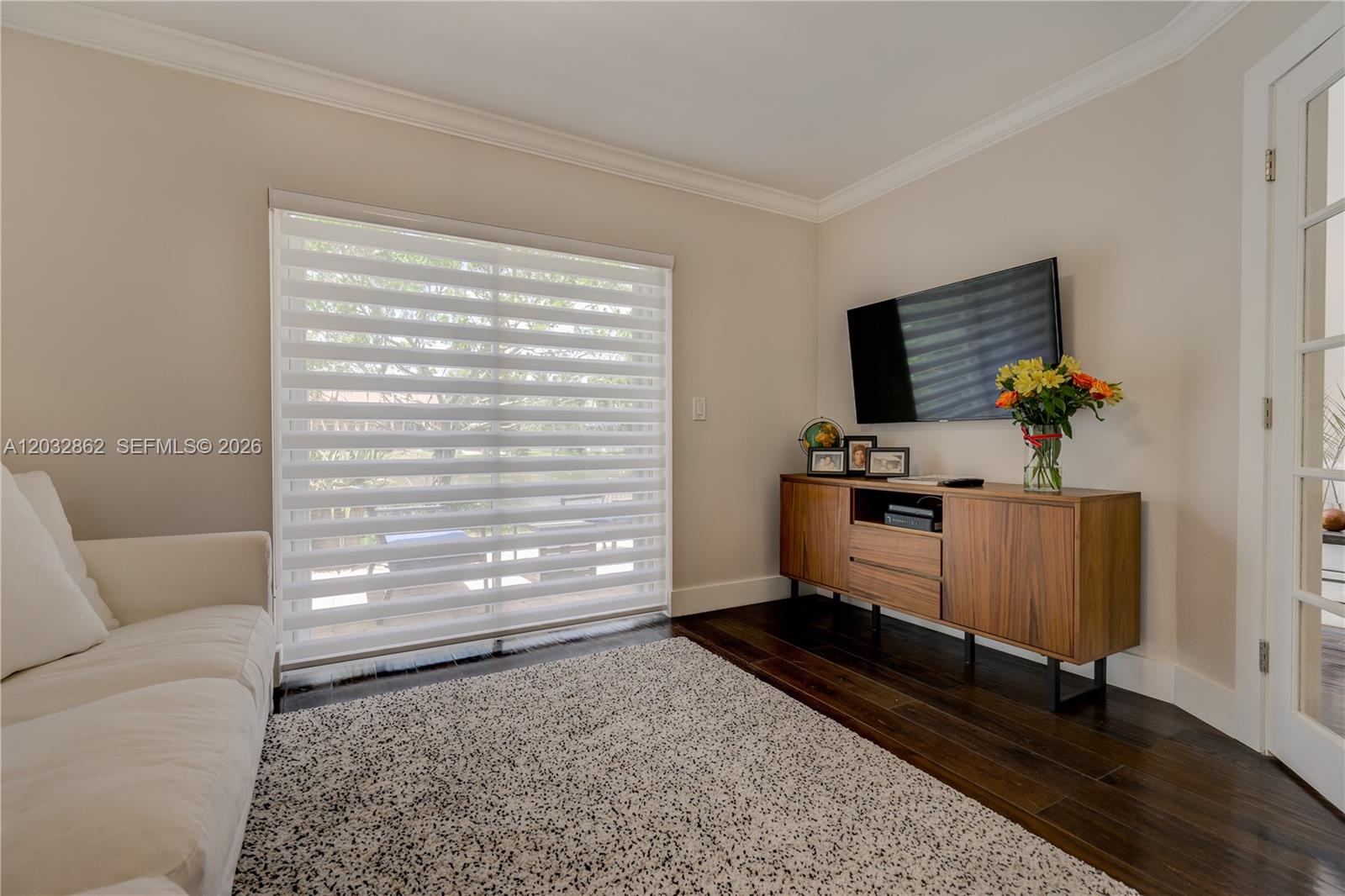 A living room features a white sofa, a wooden media console, and a large window — WESTON, FL