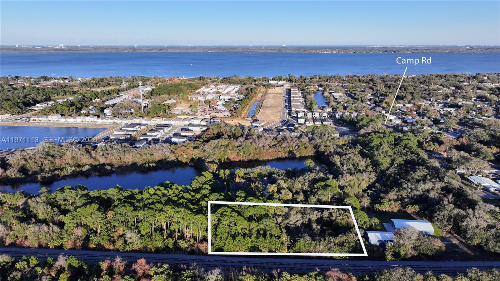An aerial view shows a rectangular wooded lot bordered by railroad tracks and nearby water — not assigned, Cocoa FL 32754, COCOA, FL