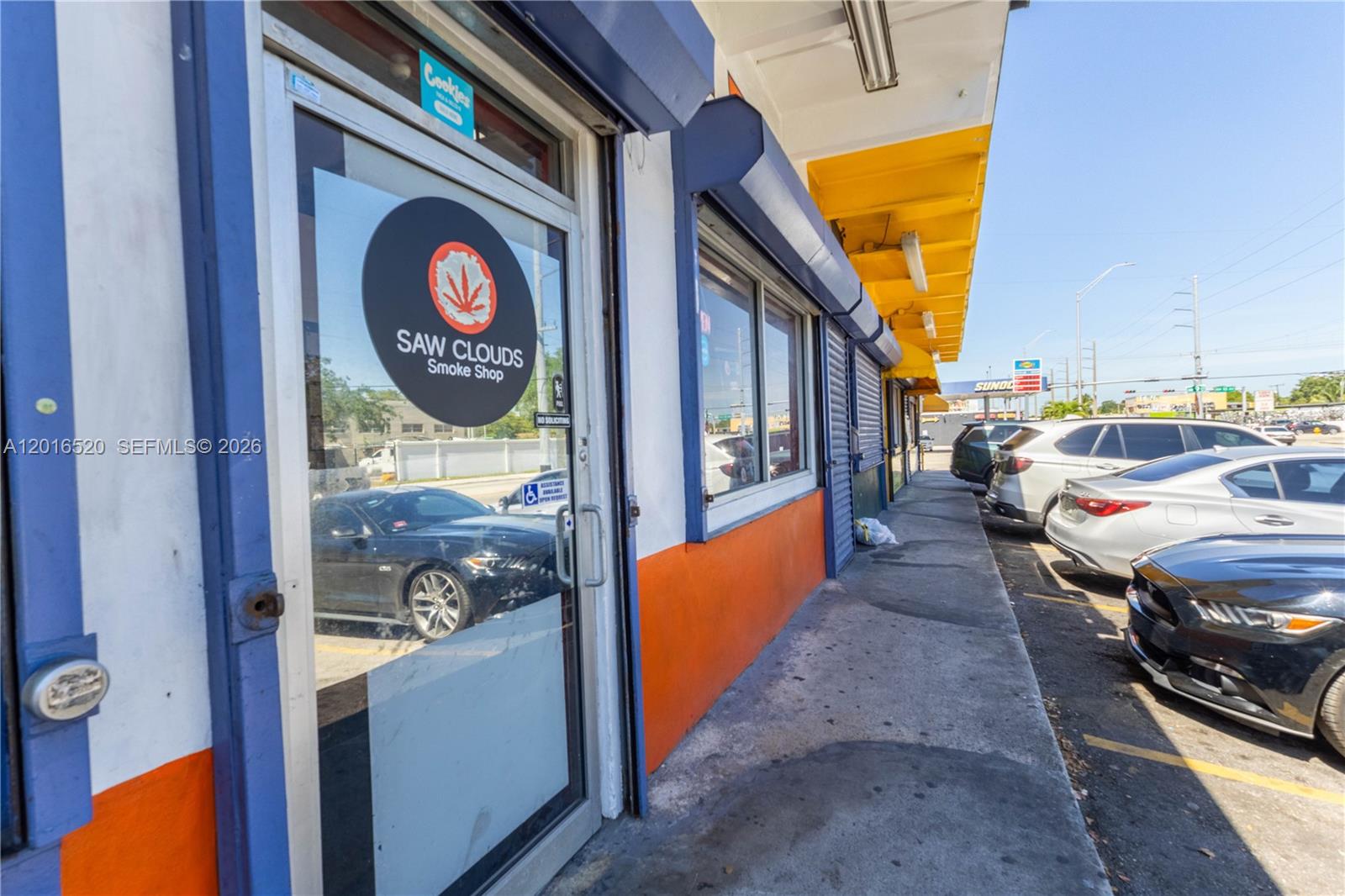The exterior of a smoke shop features a glass door, orange walls, and a yellow awning — 922 NW 36th st, Miami FL 33127, MIAMI, FL