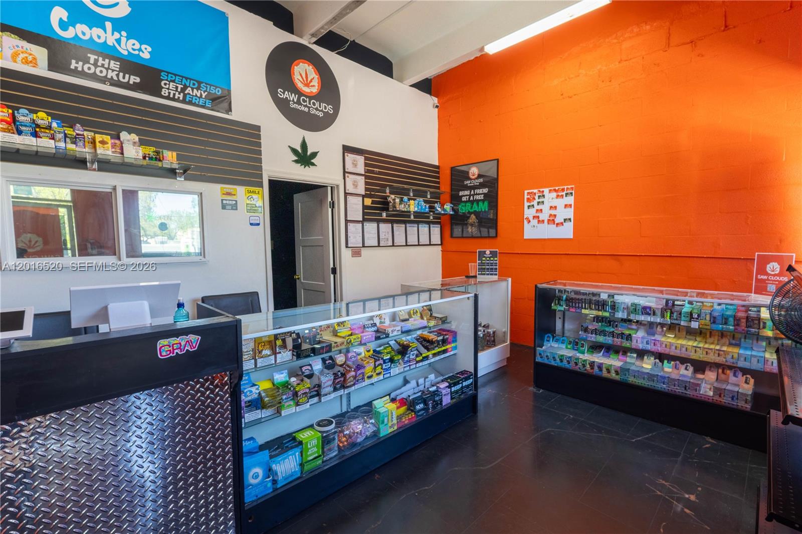 This smoke shop interior features glass display cases, orange walls, and branded signage — 922 NW 36th st, Miami FL 33127, MIAMI, FL
