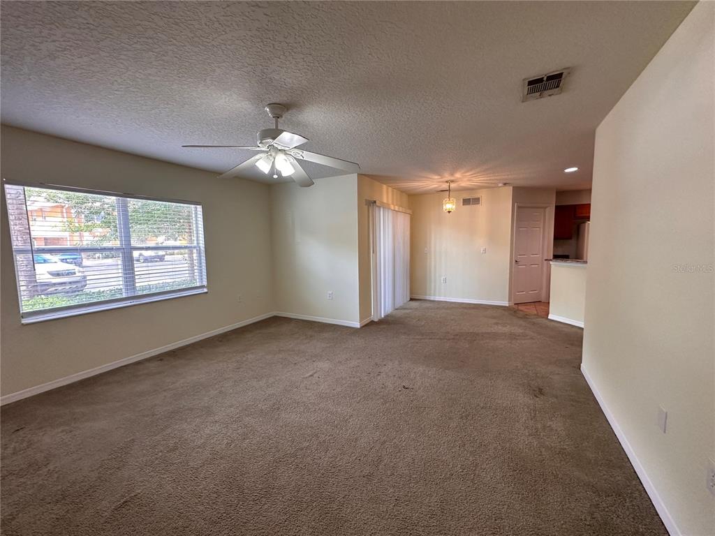 A carpeted living room features a ceiling fan, a large window, and an adjacent dining area — 4600 E MOODY BOULEVARD UNIT 12B, BUNNELL, FL