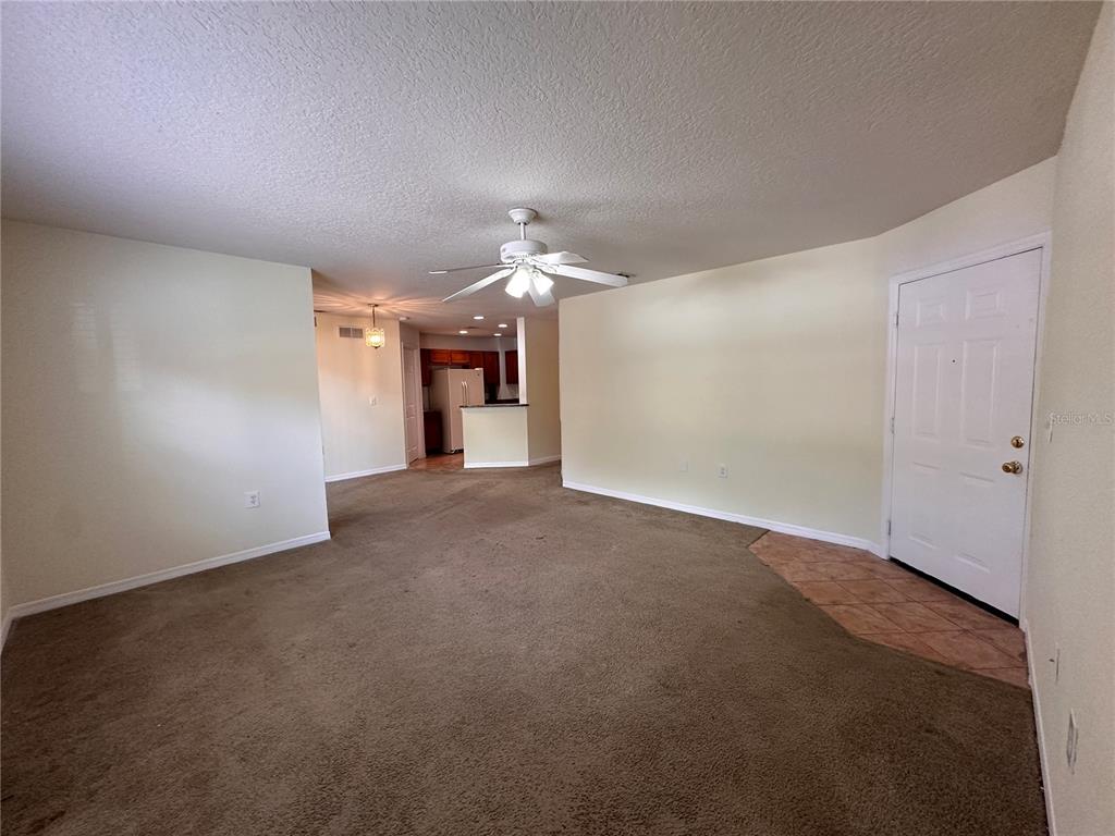 A carpeted living room features a ceiling fan, a tiled entryway, and an open kitchen — 4600 E MOODY BOULEVARD UNIT 12B, BUNNELL, FL