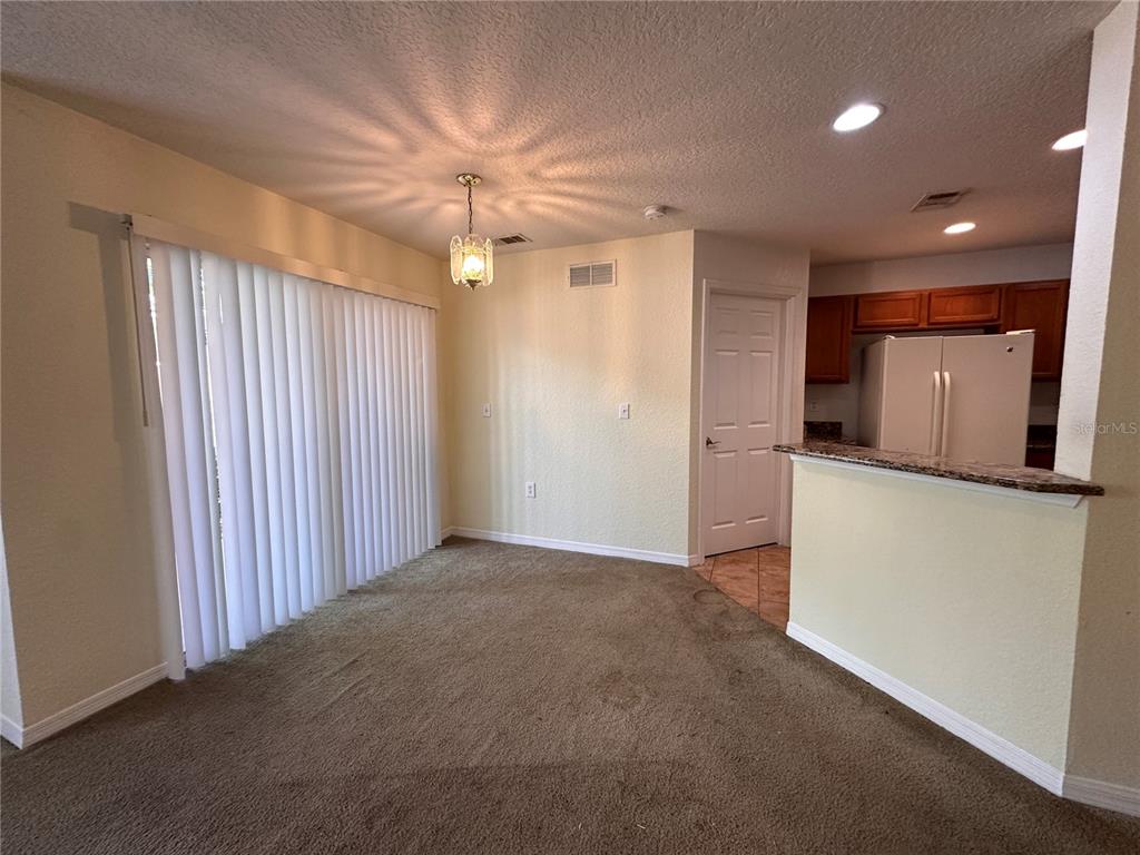 A dining area with carpeted flooring, a light fixture, and a view into the kitchen — 4600 E MOODY BOULEVARD UNIT 12B, BUNNELL, FL