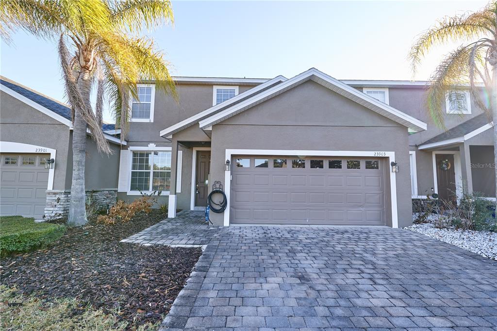 A two-story townhouse features a paved driveway, a two-car garage, and a palm tree — 23903 SARDINIA DRIVE, SORRENTO, FL