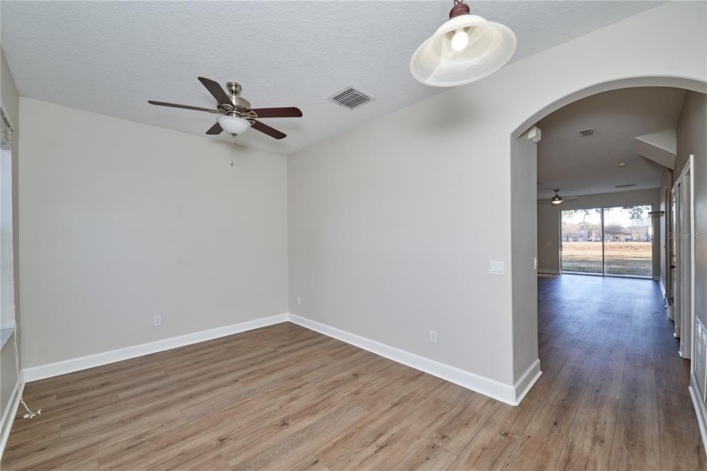 An empty room with wood-look flooring, a ceiling fan, and an arched doorway to another area — 23903 SARDINIA DRIVE, SORRENTO, FL