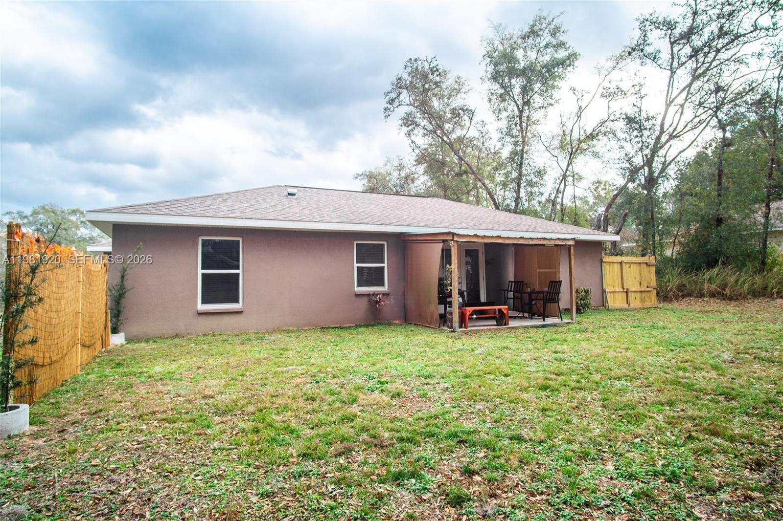 The exterior of a single-story house features a brown stucco facade, two windows, and a patio — 1123 Bucknell, Inverness FL 34450, INVERNESS, FL