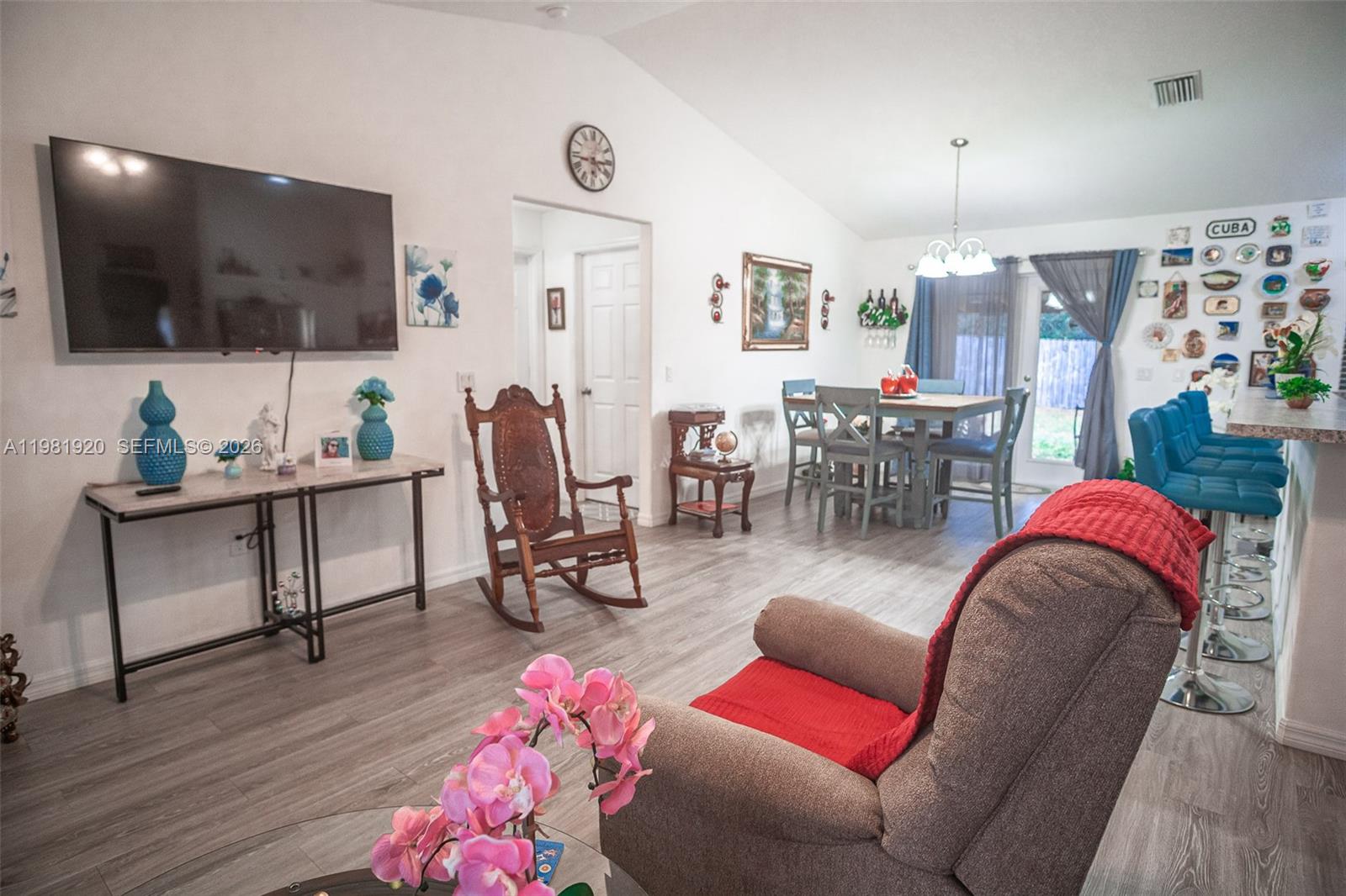 A living and dining area features light wood-look flooring, a wall-mounted television, and blue accents — 1123 Bucknell, Inverness FL 34450, INVERNESS, FL