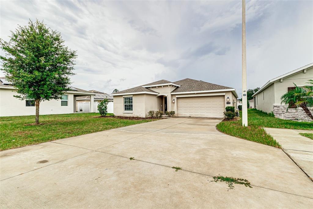 A single-story house with a beige stucco exterior, a two-car garage, and a concrete driveway — 538 PATTON LOOP, BARTOW, FL