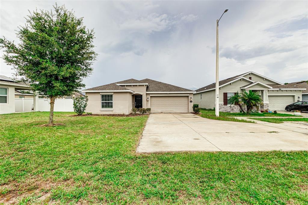 A single-story suburban house with a concrete driveway, a two-car garage, and a large tree — 538 PATTON LOOP, BARTOW, FL