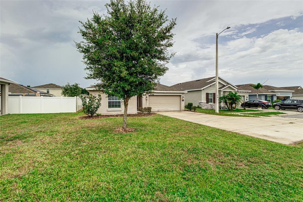A single-story house with a beige exterior, a two-car garage, and a large front tree — 538 PATTON LOOP, BARTOW, FL