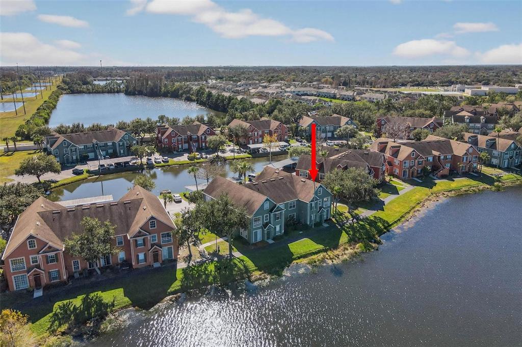 An aerial view shows a multi-story apartment building with a red arrow pointing to a unit — 9820 LAKE CHASE ISLAND WAY UNIT 9820, TAMPA, FL