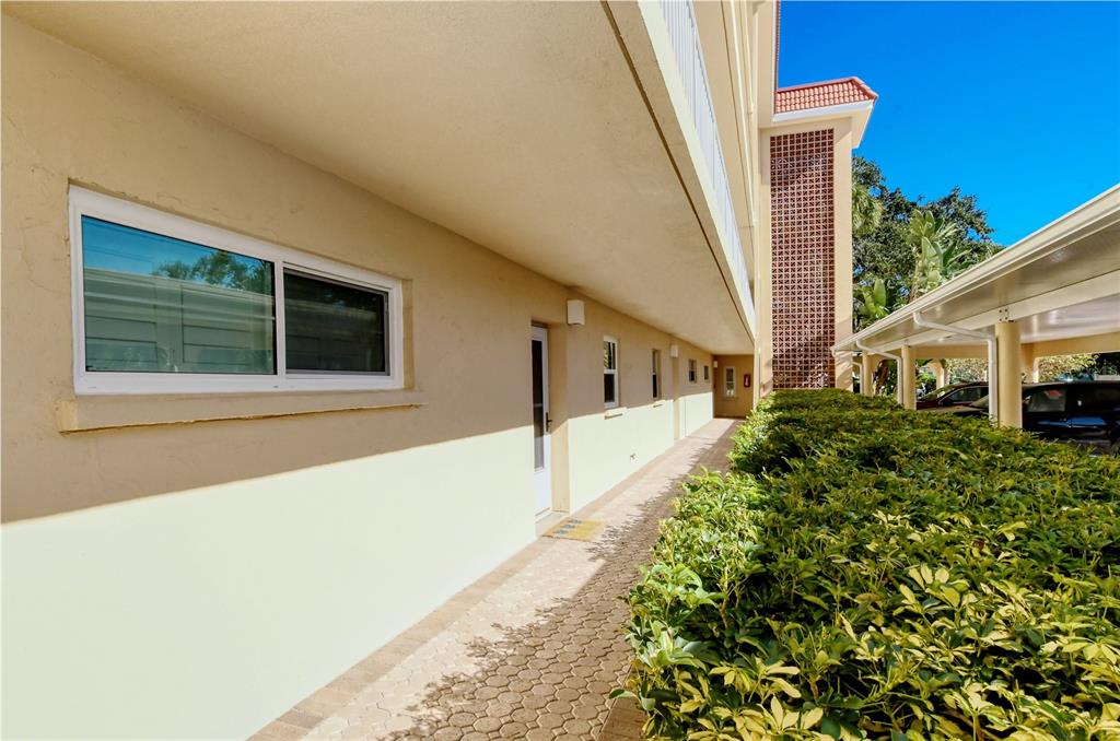 A paved walkway runs alongside a beige building exterior with a window and covered parking — 1257 S PORTOFINO DRIVE UNIT 38ALBA, SARASOTA, FL