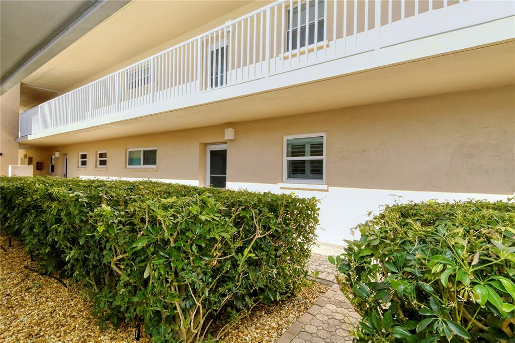 A beige two-story building exterior features a white balcony railing and a manicured hedge — 1257 S PORTOFINO DRIVE UNIT 38ALBA, SARASOTA, FL
