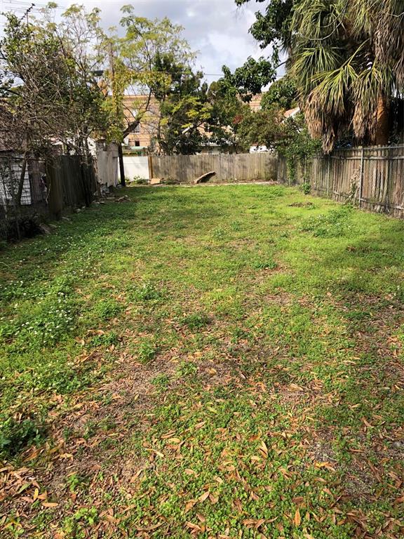 A long, narrow, grassy backyard is enclosed by wooden fences and surrounded by mature trees — 2515 W UNION STREET, TAMPA, FL