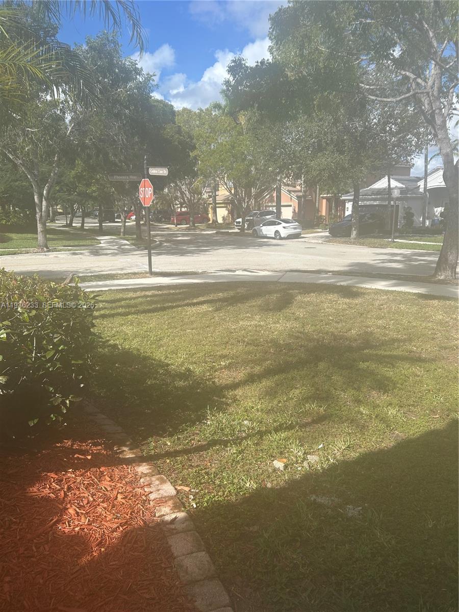 A view of a suburban street intersection with a stop sign and residential houses — 948 NW Phoenix Way, Weston FL 33327, WESTON, FL