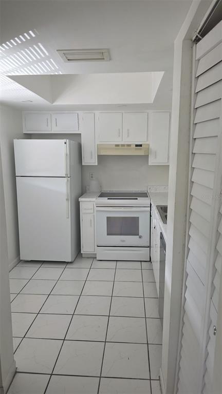 A small kitchen features white cabinets, white appliances, and light-colored tiled flooring — 6328 NEWTOWN CIRCLE UNIT B2, TAMPA, FL