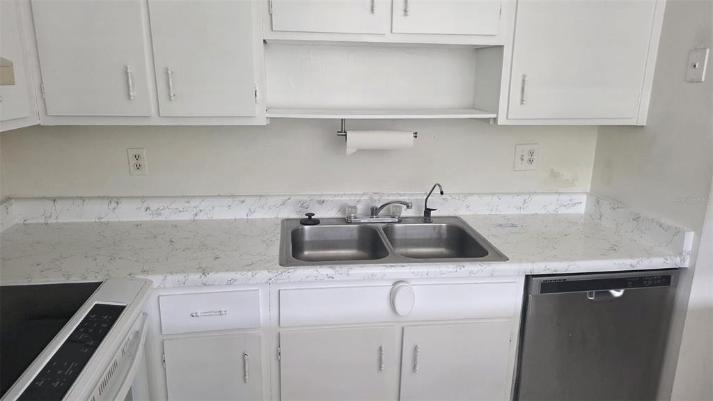 A kitchen features white cabinets, a double-basin stainless steel sink, and white marble-patterned countertops — 6328 NEWTOWN CIRCLE UNIT B2, TAMPA, FL