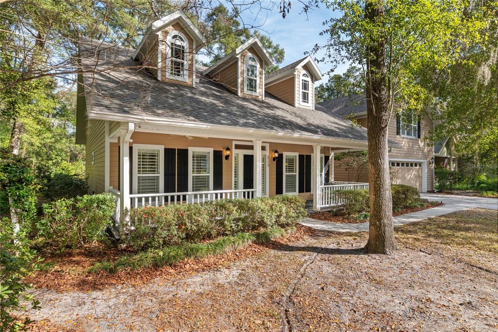 A tan two-story house features a front porch, three dormer windows, and a side garage — 3773 SW 21ST DRIVE, GAINESVILLE, FL