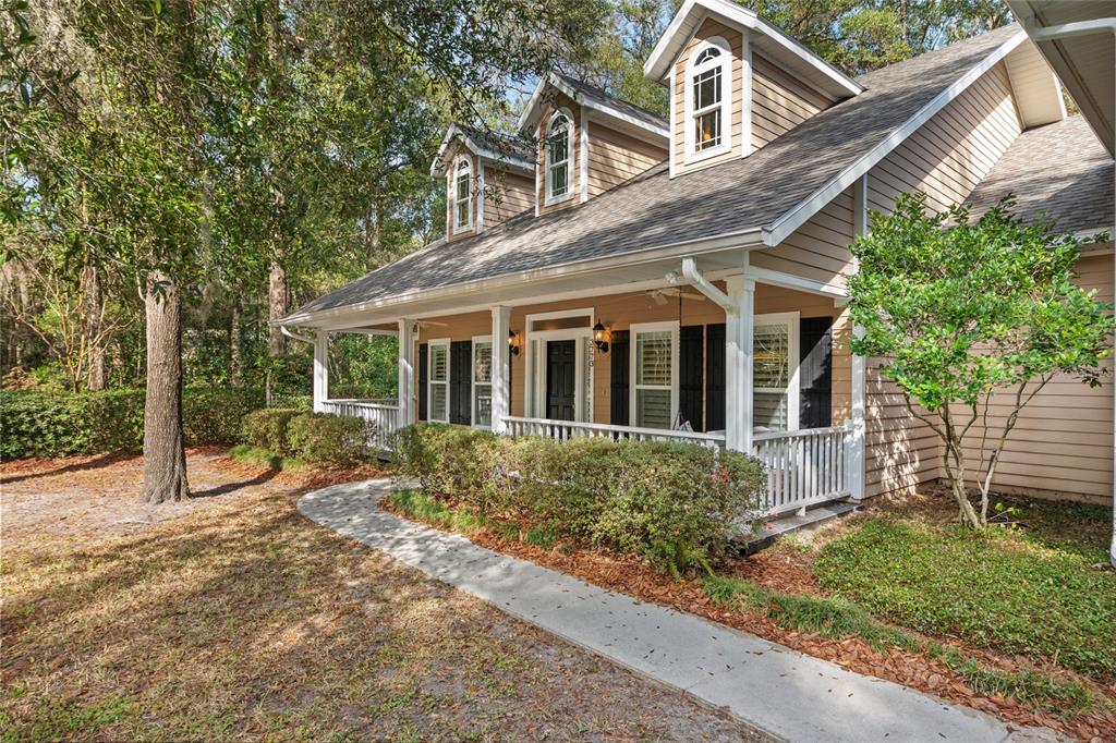 A tan house with a front porch, white railings, and three dormer windows — 3773 SW 21ST DRIVE, GAINESVILLE, FL
