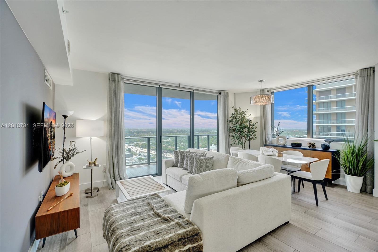 A modern living and dining area features floor-to-ceiling windows with expansive city views — 121 NE 34th St # 2809, Miami FL 33137, MIAMI, FL
