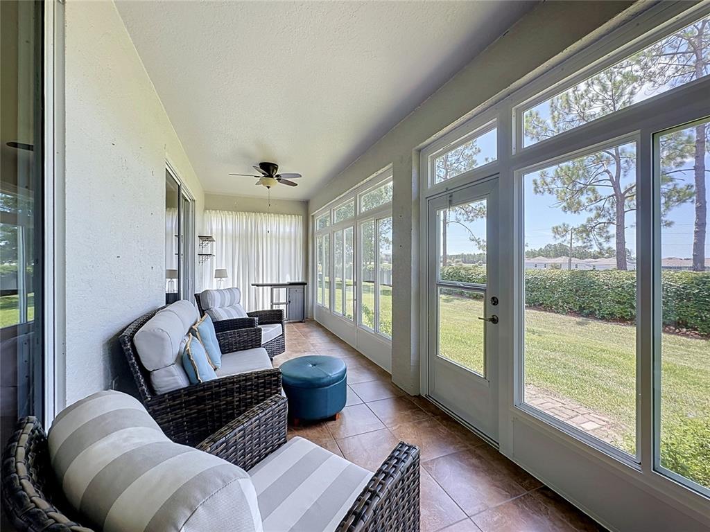 A sunroom features wicker furniture, tile flooring, a ceiling fan, and large windows overlooking grass — 4223 KINGSLEY STREET, CLERMONT, FL